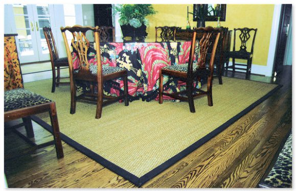 A dining room table with chairs and a rug.