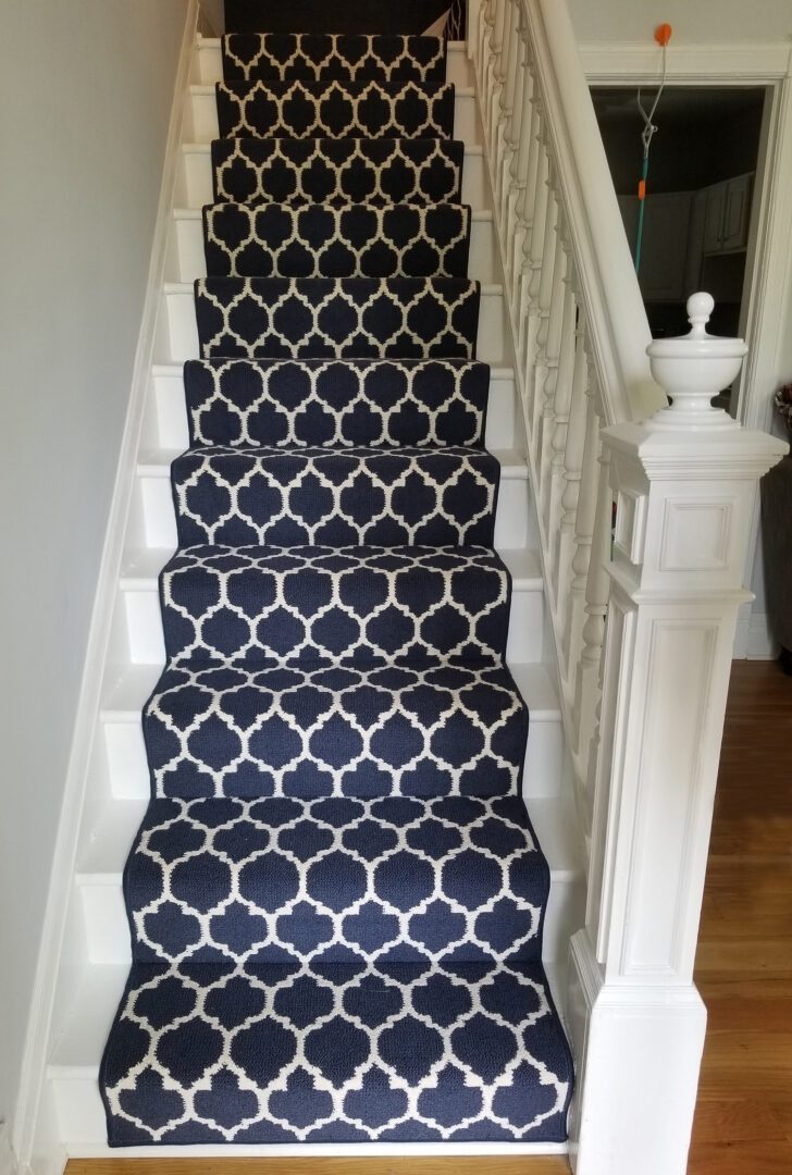 A staircase with blue and white carpet on the bottom of it.