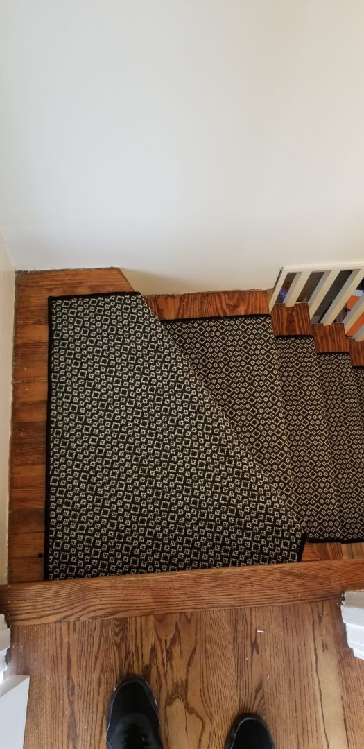 A wooden floor with stairs and a rug on it