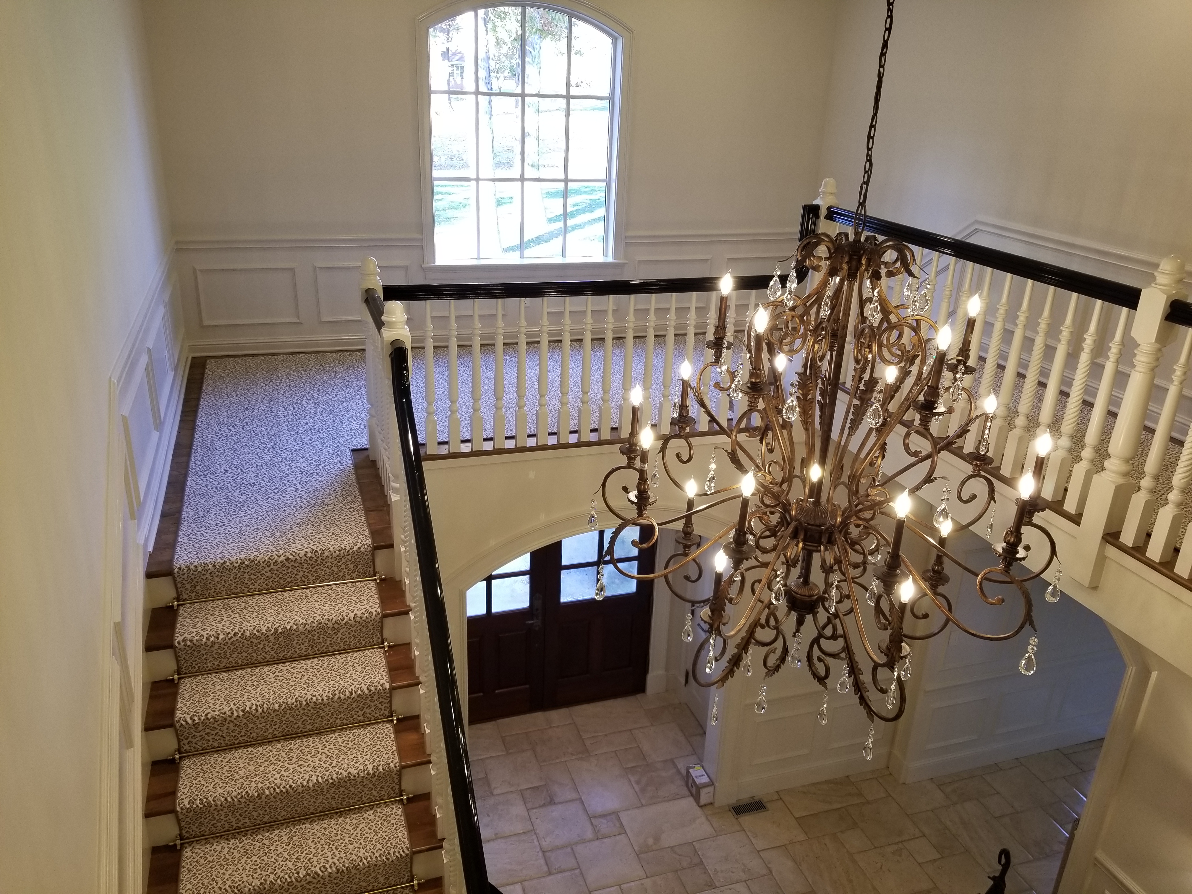 A chandelier hanging from the ceiling in front of stairs.