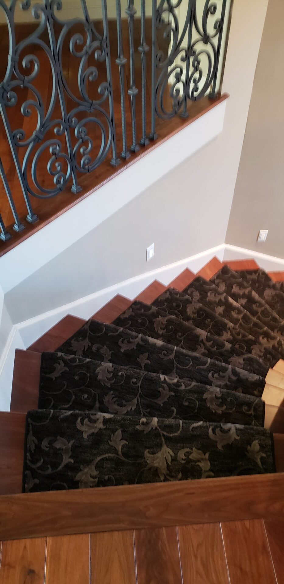 A staircase with black and brown carpet on the bottom of it.