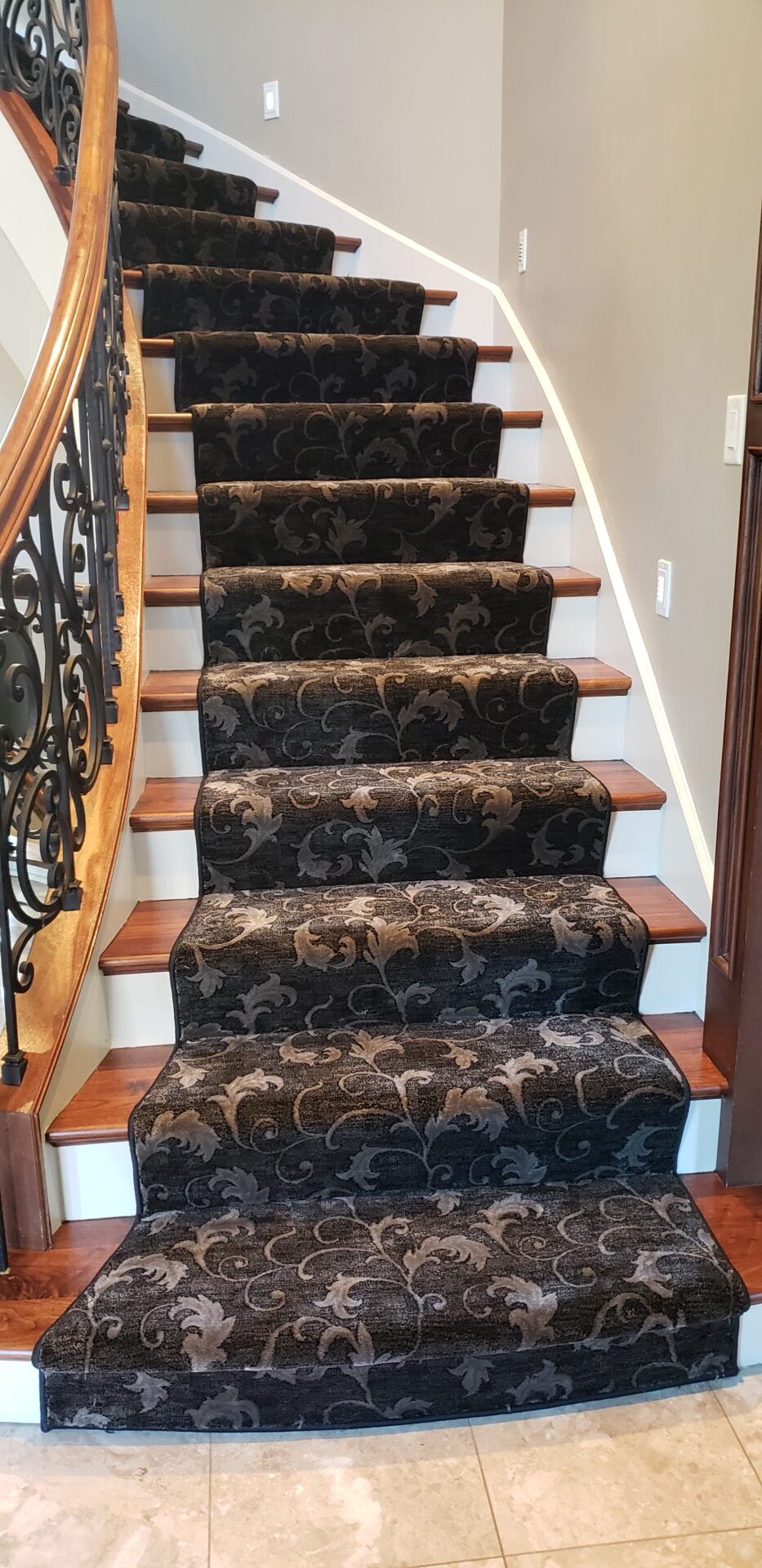 A staircase with brown and black carpet on the bottom of it.