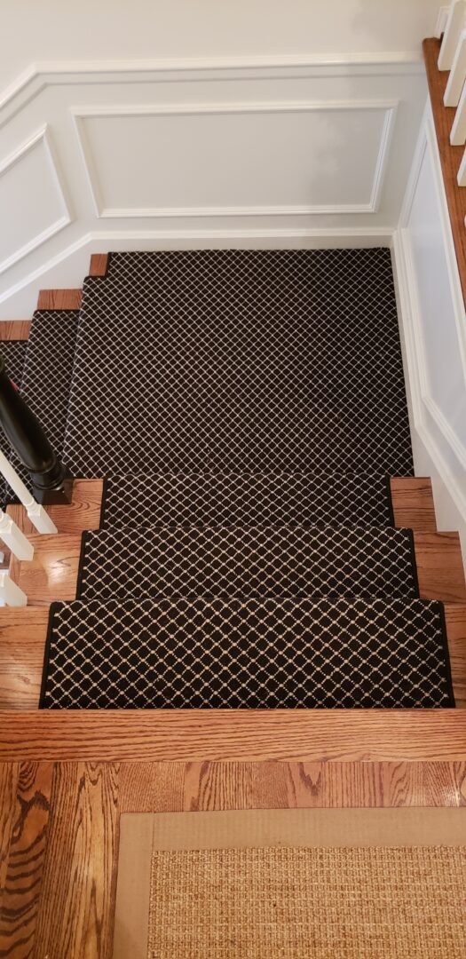 A black and brown stair runner on the bottom of stairs.